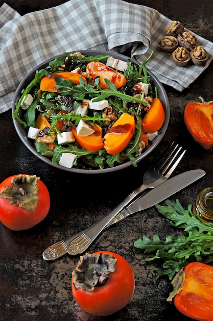 Salade saine avec kaki, roquette, noix et fromage feta. Nourriture de fitness. Superfoods Vitamine automne kaki salade.