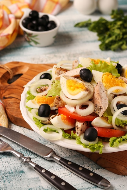 Salade saine de laitue biologique au poulet, tomates, œufs, olives noires et oignons blancs