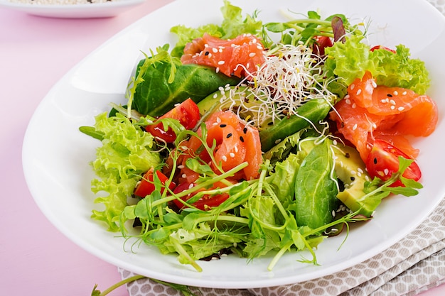 Salade saine avec légumes frais, tomates, avocat, roquette, graines et saumon