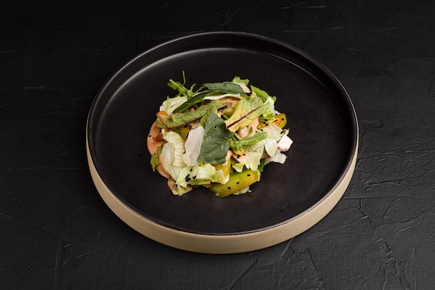 Salade de salade de légumes frais et d'herbes sur une vue de côté de fond noir