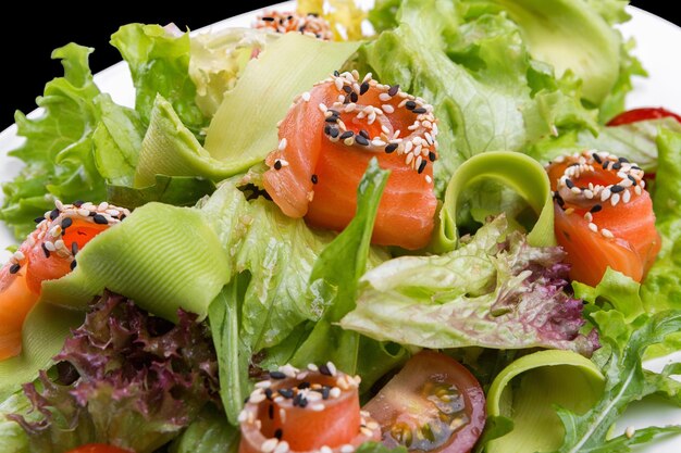 Salade de saumon à l'avocat sur une assiette sur fond sombre