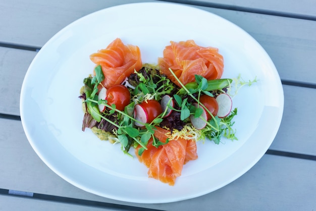 Salade de saumon avec mélange de légumes sur une plaque blanche