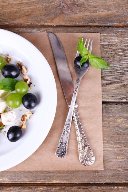 Salade savoureuse au raisin et fromage sur table en bois