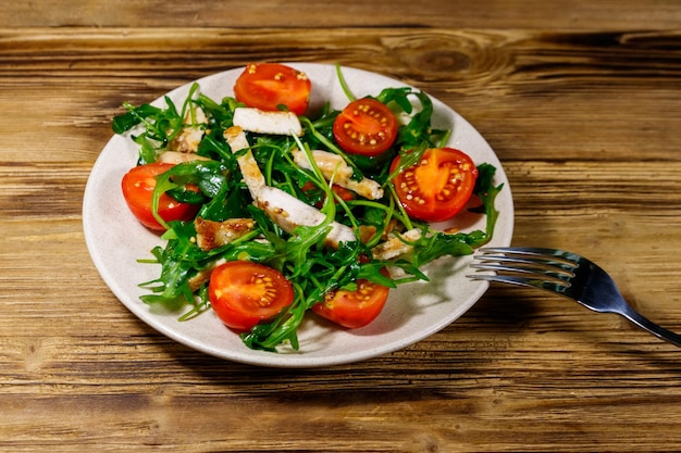 Salade savoureuse de poitrine de poulet frite roquette fraîche et tomates cerises sur table en bois