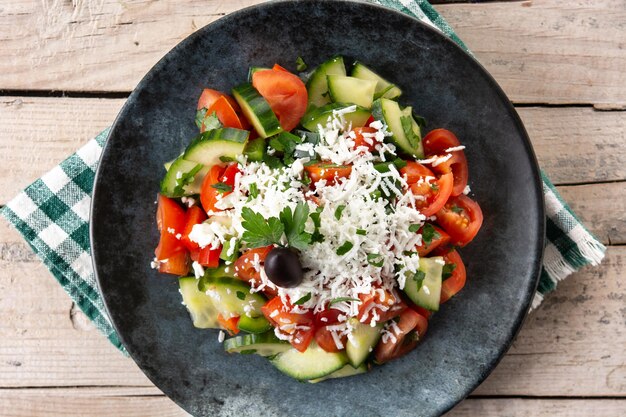 Salade de shopska bulgare traditionnelle avec concombre tomate et fromage sirene bulgare sur table en bois