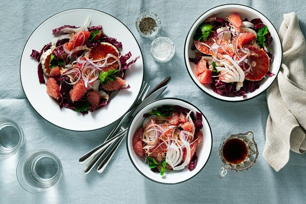 Salade sicilienne au fenouil, oranges, pamplemousse et radicchio salade avec vinaigrette balsamique sur une nappe en lin bleu.