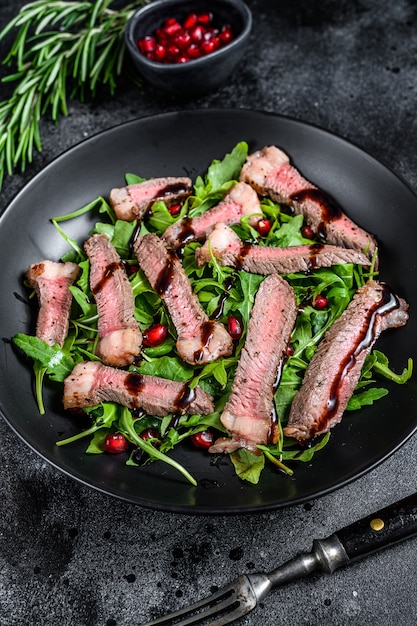 Salade de steak de boeuf grillé avec roquette, grenade et légumes verts.