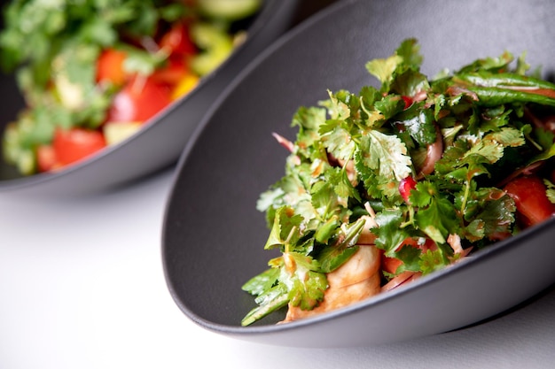 Photo salade de suluguni et tsitsmat dans une assiette sombre sur fond clair
