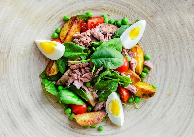 Salade de thon avec laitue, oeufs et tomates sur plaque de bois