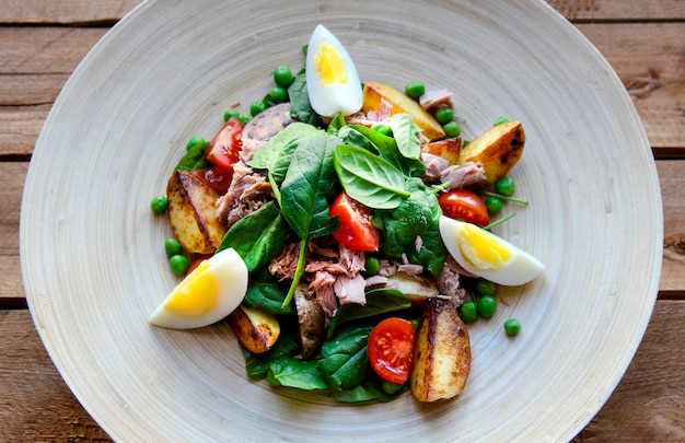 Salade de thon avec laitue, oeufs et tomates sur plaque de bois