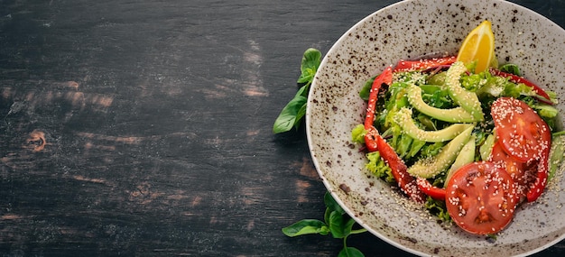 Salade avec tomate avocat et légumes frais Sur un fond en bois Vue de dessus Espace de copie