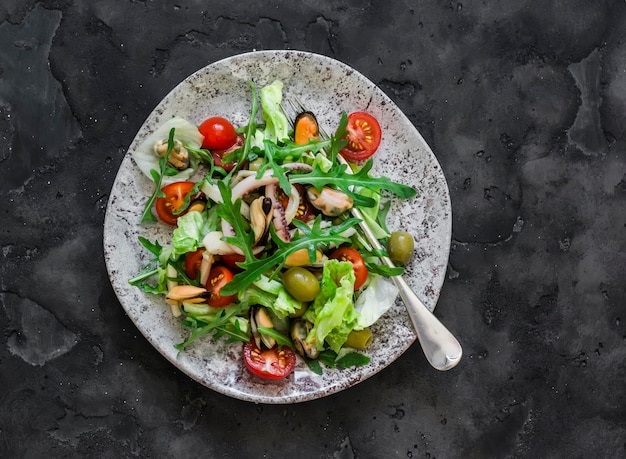 Salade de tomates cerises à la roquette et de fruits de mer sur une vue de dessus de fond sombre