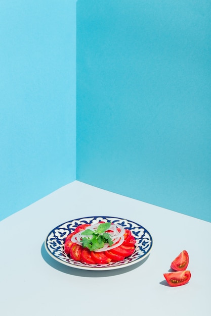 Salade de tomates coupées à l'oignon et au basilic sur une assiette bleue orientale minimalisme moderne p...