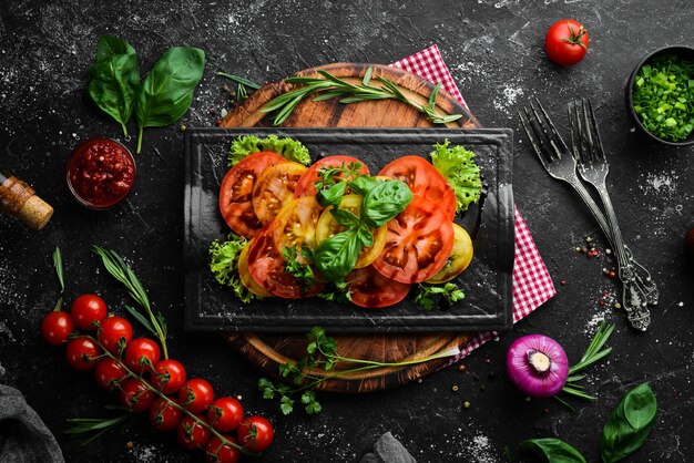 Salade de tomates fraîches et basilic sur une assiette en pierre noire Vue de dessus Espace de copie gratuit