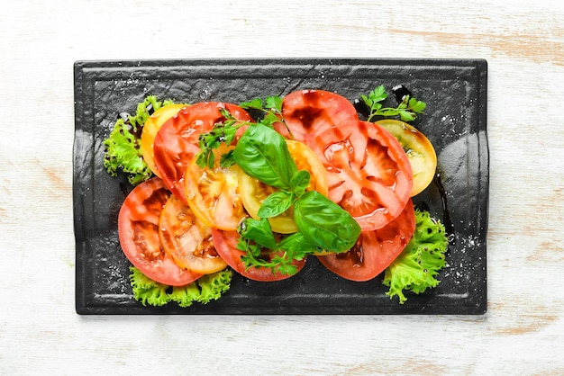 Salade de tomates fraîches et de basilic sur une assiette en pierre noire Vue supérieure Espace de copie libre