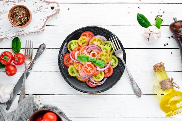 Salade de tomates fraîches et d'oignons dans une assiette noire Sur le vieux fond Vue de dessus Espace libre pour votre texte