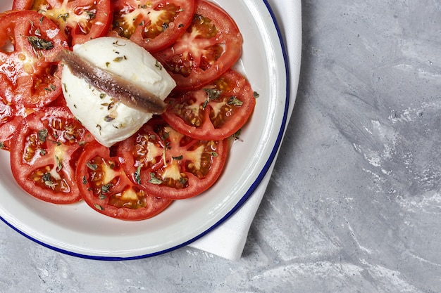 Salade de tomates maison saine avec mozzarella, anchois et origan