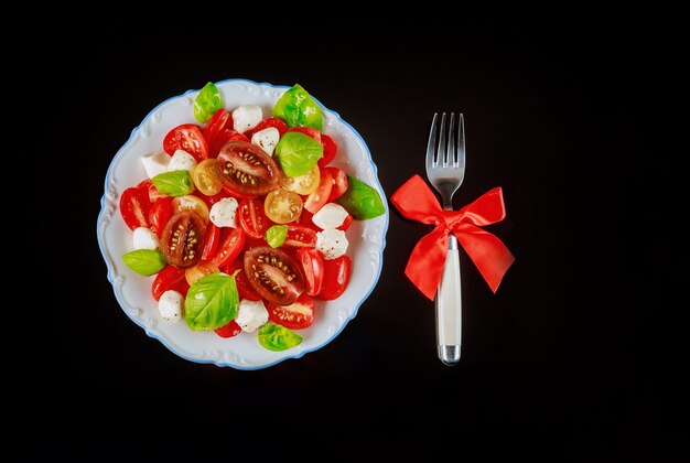 Salade de tomates et mozzarella en tranches avec une fourchette pour le dîner de Noël. Plat végétarien.