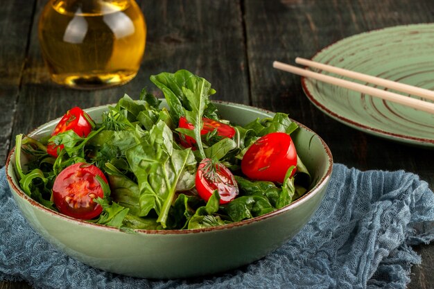 Salade de tomates, roquette et épinards sur une table en bois noir