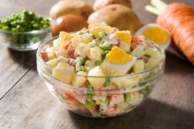 Salade traditionnelle russe dans un bol. Salade Olivier sur une table en bois.