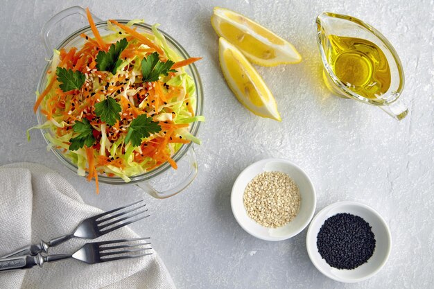 Salade végétale saine à base de chou et de carottes garnie de persil, de cumin et de graines de sésame et garnie d'huile d'olive et de citron