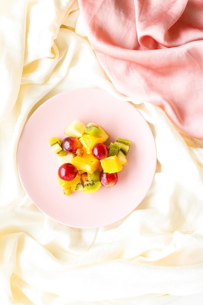 Salade végétalienne de fruits frais sur une assiette rose nutrition saine et désintoxication