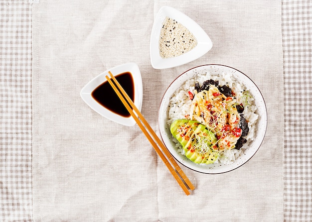 Salade végétalienne avec riz, chou kimchi mariné, avocat, nori et sésame sur bol.