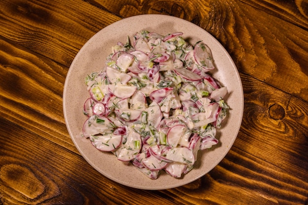 Salade végétarienne aux oignons verts de radis et à la crème sure sur une plaque en céramique Vue de dessus