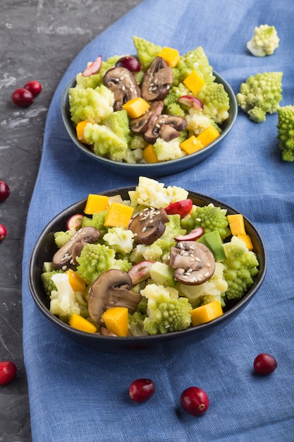 Salade végétarienne de chou romanesco, champignons, canneberge, avocat et citrouille sur une surface en béton noir. vue de côté.