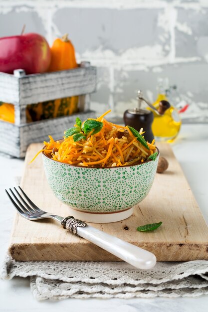 Salade végétarienne à la citrouille, pommes et raisins secs sur une surface légère