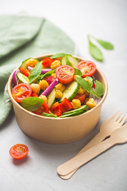 Salade végétarienne de haricots de pois chiches préparée avec des tomates et du concombre dans un bol en papier. Vaisselle zéro déchet