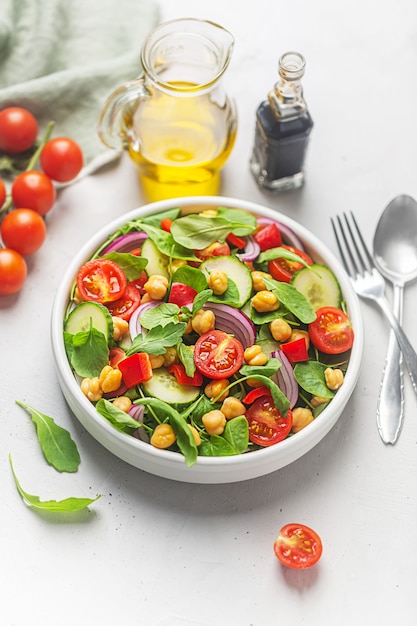 Salade végétarienne de haricots de pois chiches préparée avec des tomates, du concombre, de l'oignon rouge, de la salade de cresson, de la roquette et de l'huile d'olive. Les pois chiches sont riches en protéines et en fibres