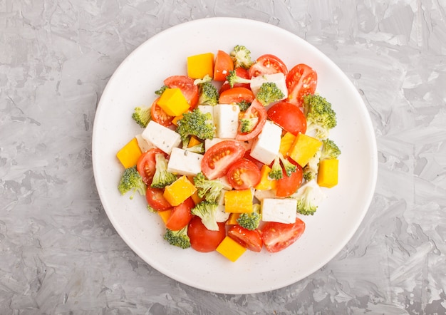 Salade végétarienne sur une plaque en céramique blanche sur un béton gris