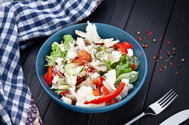 Salade végétarienne de tomate et laitue dans un bol bleu sur une surface en bois sombre