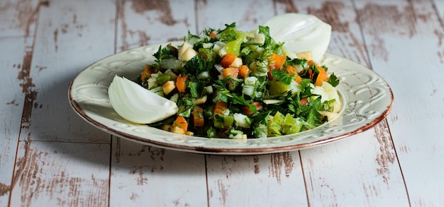Salade verte aux pommes de terre poivrons carottes aneth persil pomme oignon dans une assiette vintage sur une table en bois