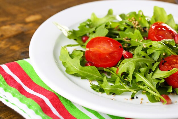 Salade verte à base de tomates roquette et de sésame sur plaque sur fond de bois