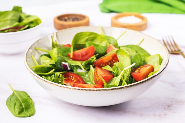 Photo salade verte d'été dans une assiette de bol blanc sur une table grise