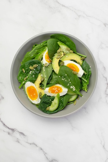 Salade verte fraîche avec avocat aux œufs et épinards sur fond gris dans une assiette grise