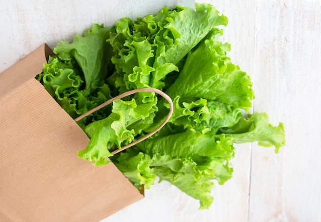 Salade verte fraîche dans un emballage écologique en papier beige, vue de dessus