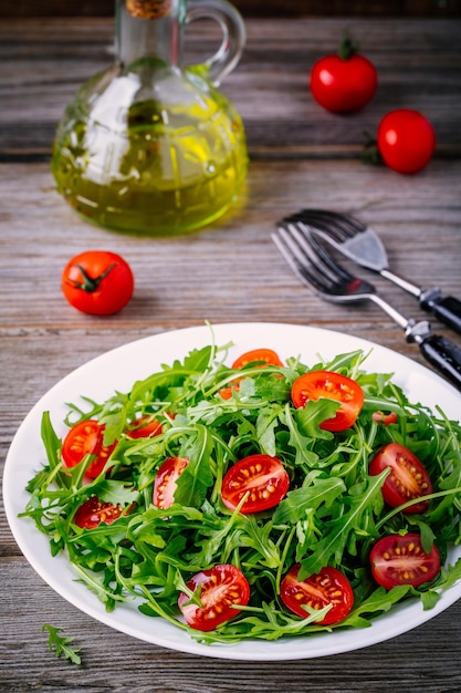 Salade verte fraîche avec roquette et tomates rouges sur fond de bois rustique