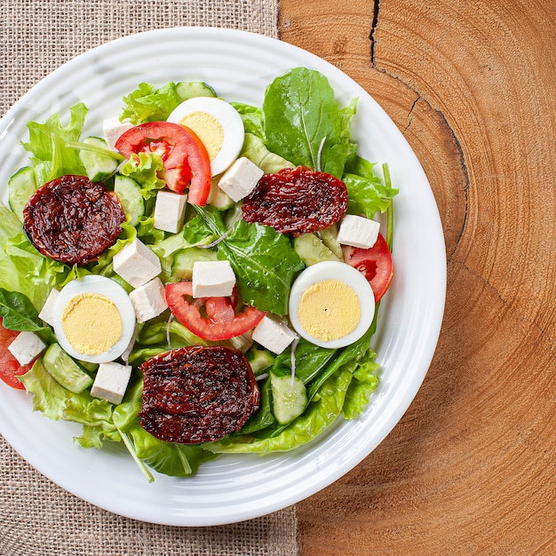 Salade verte avec laitue, roquette, concombre, fromage, tomates séchées et œuf à la coque.