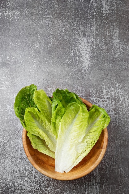 Salade verte lavée fraîche dans un bol en bois prêt pour la cuisson. Ingrédients pour la cuisine, régime végétarien, alimentation saine. Vue de dessus, espace pour le texte.