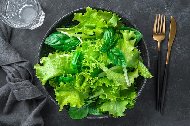 Salade verte mélangée fraîche dans une assiette sur fond noir