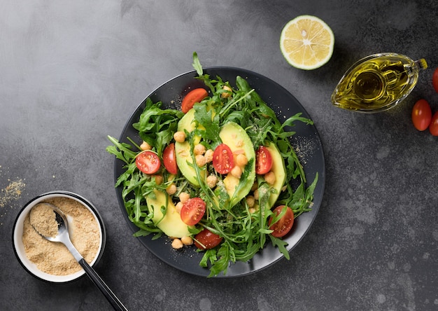 Salade verte avec des pois chiches à l'avocat et des flocons de levure nutritionnelle sur une assiette noire Détox alimentaire végétalien