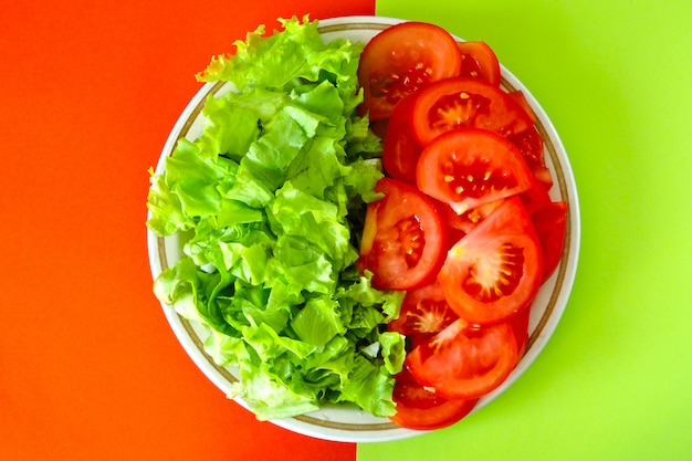 Salade verte et tomate rouge sur une surface rouge-vert