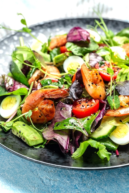 Salade verte avec tomates cerises, concombre, avocat, œufs et crevettes fumées, mesclun. La nourriture saine. Manger propre. Fond de recette de nourriture. Fermer.