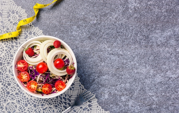 Saladier sain avec tomates légumes frais mélangés dans un plat et ruban à mesurer