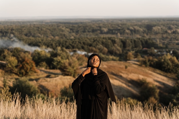 Photo salah. une femme africaine en robe noire prie en dieu. religion islamique