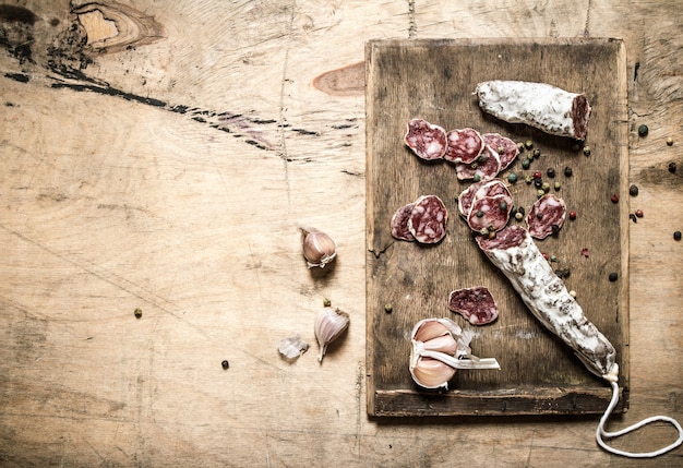 Salami aux épices et ail tranché sur une planche de bois.