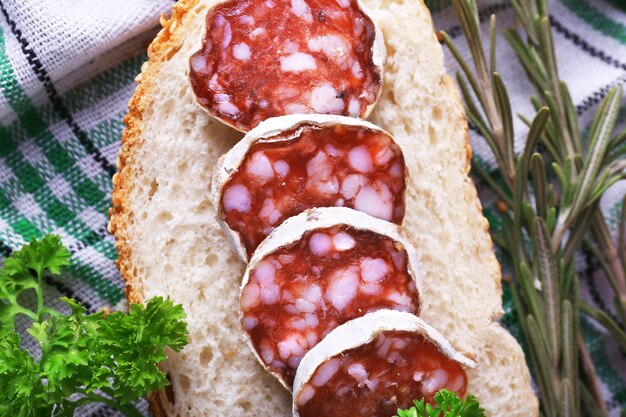 Photo salami français avec des tomates au pain et du persil sur fond de tissu